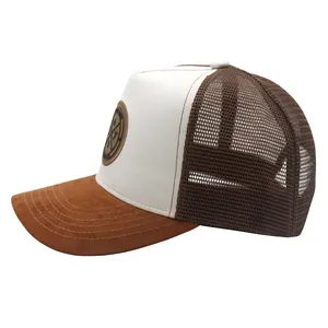 Detailed side view of trucker hat mesh panels and round leather badge on brown faux suede