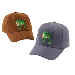 Détail de la broderie de dinosaure vert sur des casquettes de baseball marron et bleues