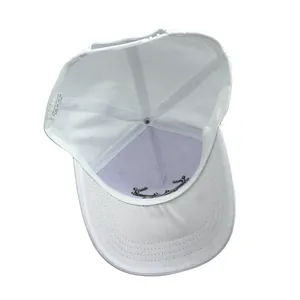 Detail view of white baseball cap interior showing 100 percent polyester label and buckle