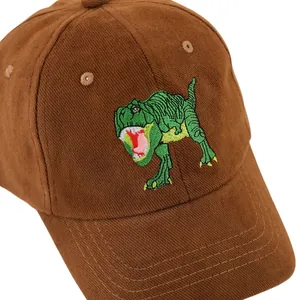 Détail d'une casquette enfant en velours marron avec broderie dinosaure vert sur blanc