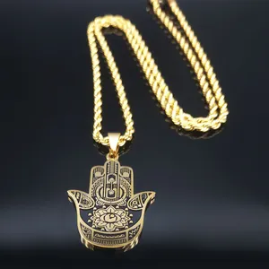 Gros plan du pendentif main de Fatma dorée avec œil gravé sur une surface noire réfléchissante