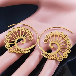 Detail of bohemian gold hollow carved spiral earrings on hand model showing large scale