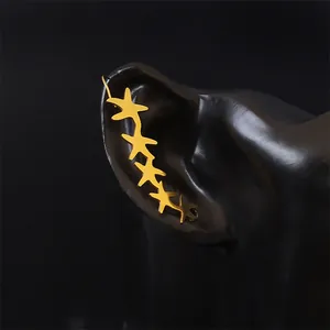 Close-up of golden starfish ear crawler earrings on a professional black model display