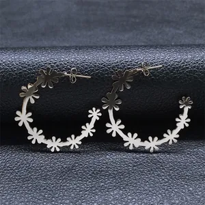 Detailed close-up of gold hoop earrings with white floral accents on black leather