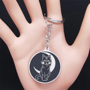 Detail of crescent moon cat keychain in stainless steel held in hand for scale