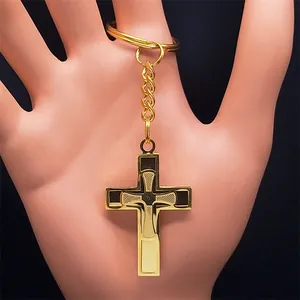 Detail of a golden cross keychain with polished texture held by a hand on black background
