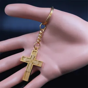 Polished gold stainless steel cross keychain with textured center on a hand model