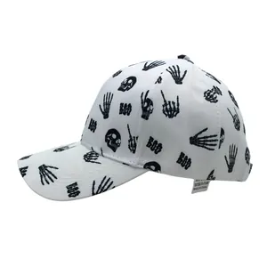 Détail d'une casquette blanche avec imprimés crânes, mains squelettes et inscription BOO
