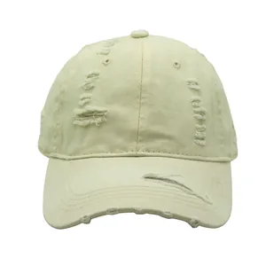 Detail of distressed ripped holes on a beige vintage washed cotton baseball cap