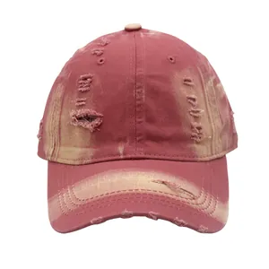 Detailed view of distressed burgundy cotton baseball cap with vintage worn-out holes