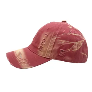Detail view of burgundy washed cotton baseball cap featuring vintage distressed torn holes