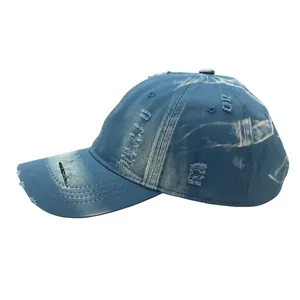 Detailed view of the distressed dark blue washed denim baseball cap with frayed holes