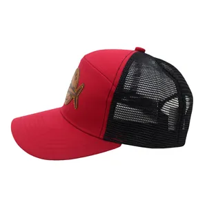 Detail der rot-schwarzen Trucker-Kappe mit braunem Lederpatch und Fischereimotiv-Logo