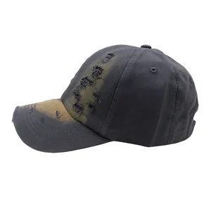 Macro shot of charcoal grey distressed baseball cap with yellow paint splatter and ripped details