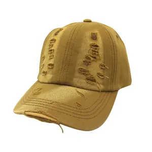 Detailed close-up of distressed ripped holes on a vintage mustard yellow baseball cap