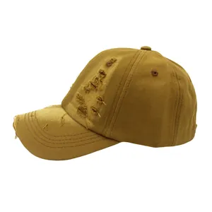 Detail of distressed ripped brim on a vintage khaki cotton baseball cap with torn fabric