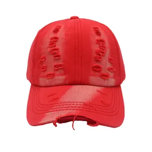 Detail of red vintage distressed baseball cap with ripped holes and washed cotton texture