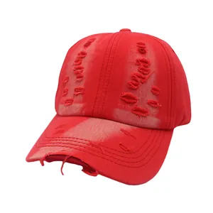Close-up detail of the distressed ripped holes and cotton twill texture on a red baseball cap