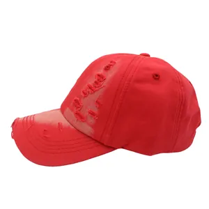 Detail of red vintage washed baseball cap featuring distressed holes and classic stitching