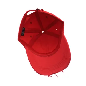 Detail view of red cotton baseball cap showing distressed brim and metal buckle