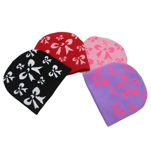 Détail de quatre bonnets en maille jacquard avec motifs nœuds sur fond blanc neutre