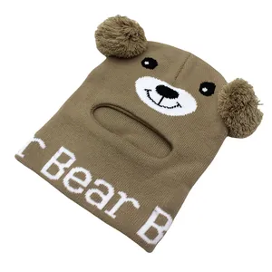 Dettaglio del passamontagna in maglia marrone a forma di orso con pompon e viso