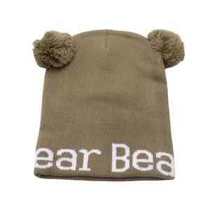 Dettaglio cappello in maglia marrone con pompon e ricamo bianco Bear per bambini