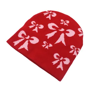 Détail du bonnet en tricot rouge avec motifs nœuds jacquard rose et texture douce