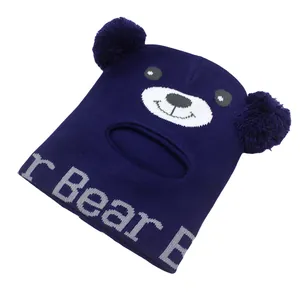 Dettaglio del cappello in maglia blu scuro con pompon e motivo a forma di viso di orso