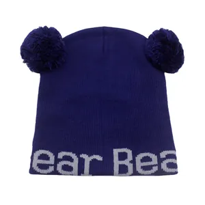 Dettagli del berretto lavorato a maglia viola scuro con pompon e scritta ear Bea tessuta