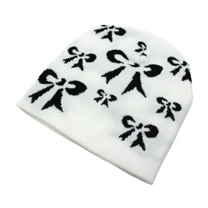 Gros plan sur la maille tricotée et les motifs de nœuds noirs sur le bonnet blanc