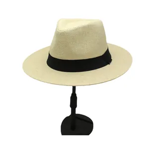 Detail of breathable beige straw fedora hat featuring a stylish black ribbon band on a stand