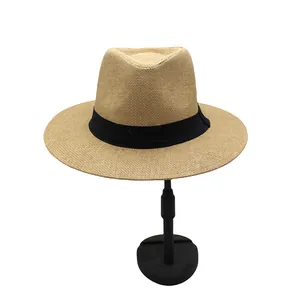 Detailed macro view of khaki straw fedora hat featuring black ribbon and woven texture