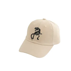 Close-up of beige cotton baseball cap featuring black dinosaur skeleton embroidery