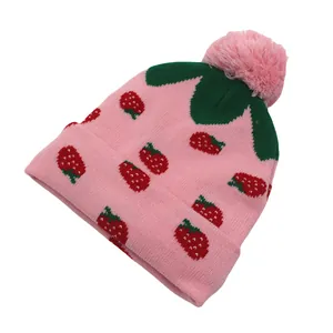 Roze gebreide muts voor meisjes met aardbeienpatronen en een zachte pluizige pompon