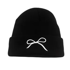 Knitted beanie for autumn and winter featuring a minimalist white bow embroidery