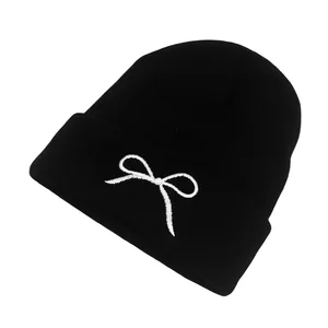 Classic black knitted beanie featuring white bow embroidery for outdoor winter warmth