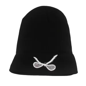Detail of black knitted beanie featuring white bow embroidery and high quality texture