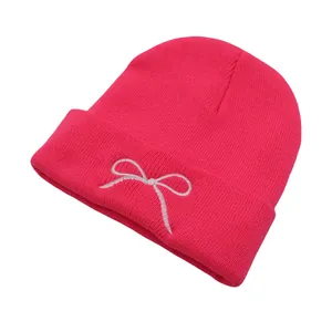Detail of hot pink knit beanie showing bow embroidery texture and fine ribbed cuff