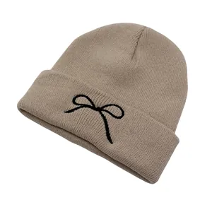 Close-up of the delicate black bow embroidery on a khaki knitted beanie hat cuff