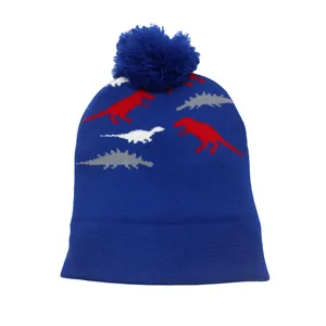 Détail du bonnet en tricot bleu marine avec motifs de dinosaures et pompon doux en haut