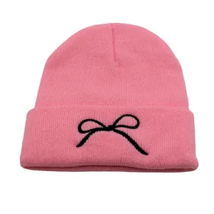 Close-up of pink knitted beanie featuring black bow embroidery and ribbed texture