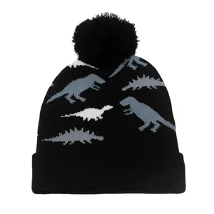 Détail du bonnet en tricot noir avec motifs de dinosaures et un pompon sur le dessus