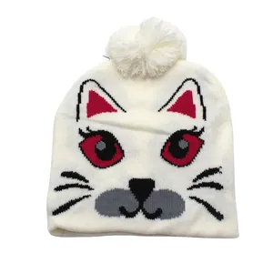 Détail d'un bonnet en tricot blanc avec motif chat, pompon et broderie mignonne