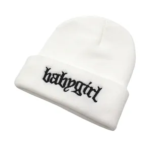Nahaufnahme der schwarzen Babygirl-Stickerei auf einer weißen Strickmütze für Winter