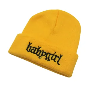 Detail der gotischen Babygirl-Stickerei auf dem Umschlag der gelben Strickmütze für Winter