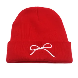 Red knit beanie with white bow embroidery for men and women, perfect for winter warmth