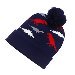 Détail du bonnet en tricot bleu marine avec motif dinosaure jacquard et pompon doux