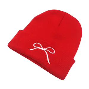 Close-up of red knit beanie showing fine woven texture and white ribbon embroidery
