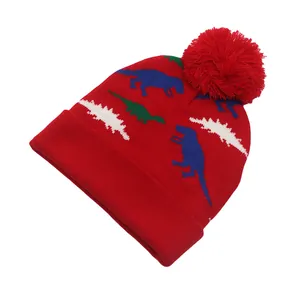Gros plan du bonnet tricoté rouge pour enfant avec motif dinosaure et gros pompon